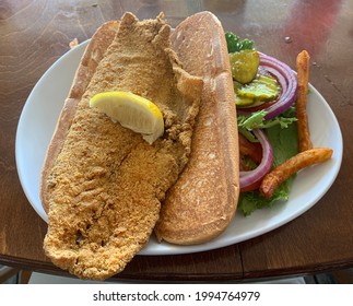 Catfish Po’Boy Sandwich With Huge Fillet Of Catfish And Fries.