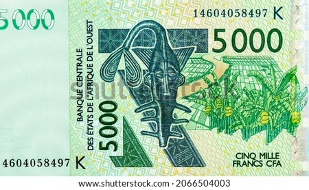 Catfish shaped brass weight of the Ashanti people for weighing gold dust, banana trees. Portrait from Western African States 5000 Francs 2003 Banknotes. CFA franc is used in 14 African countries. 