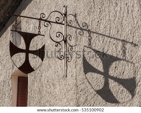 Cathar cross and its shadow in a house of Rennes-Le-ChÃ¢teau, France.