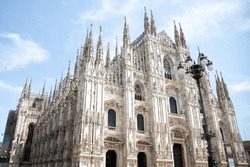 Cathedral in Milan Duomo sunny photo, a large cathedral with a clock on the front of it, an Architecture Photo by mariana.foto