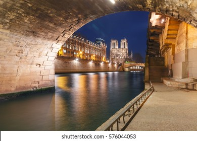 Cathedral of Notre Dame, Petit Pont and riverside of Seine river in Paris at night, France