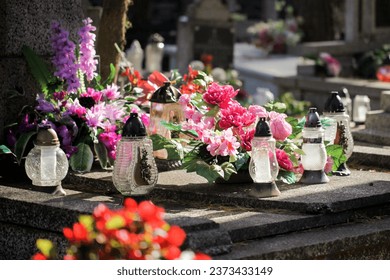 Catholic cemetery background. All saints holiday. Grave candle light. Cotton flowers. Funeral bouquets  Grave candles on marble tomb. Gray granite grave. Sunlight graveyard landscape. - Shutterstock ID 2373433149