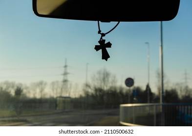 A catholic cross hanging from the windshield mirror in the car