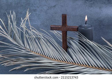 Catholic Cross with palm leaf and burning candle. Ash Wednesday, Lent season, Holy Week, Good Friday and Palm Sunday concept. Copy space.