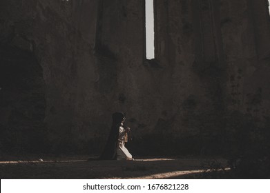 Catholic Nun Prays In The Dark Old Church. Historical Cosplay Of Vintage Church. A Woman In Old Nun Catholic Cassock