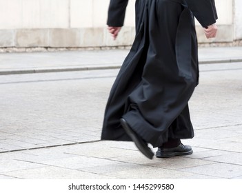 Catholic Priest In The Black Cassock Walking On The Street Solo, Only Legs Visible. Clergy, Faith, Christianity And Calling Abstract Concept