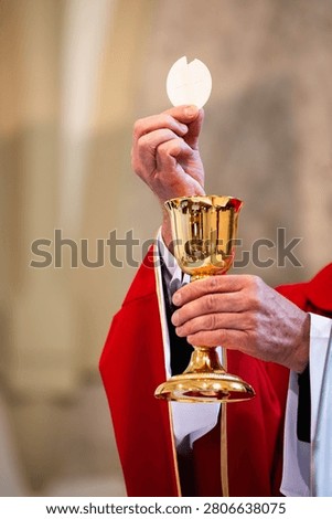 Catholic priest elevating the Eucharistic host above golden chalice during Holy Mass, symbolizing faith, consecration and Christian worship