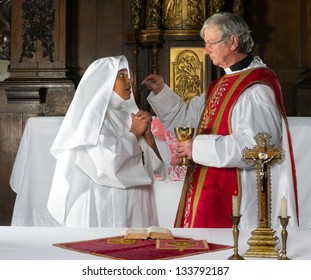 Catholic priest giving holy communion to a nun