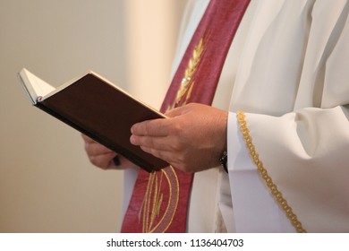 Catholic Priest Holding A Holy Book In His Hands During Sermon