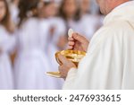 Catholic priest serving Jesus in eucharist during first holy communion IHS