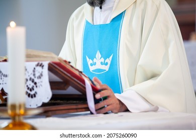 Catholic Priest In A White Robe With Blue Markings During Mass