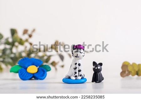 Cats and a flower made of polymer clay on a light background. Handmade decor