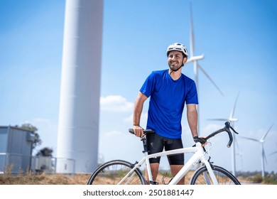 Caucasian active sportsman riding bicycle at the wind turbine field. Attractive athlete in sportswear exercise by cycling workout outdoors for health and wellness in rural area at windmill power farm. - Powered by Shutterstock