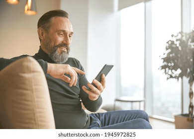 Caucasian Adult Man Is Sitting With Smartpone In Modern Cozy Office Lounge Zone