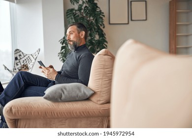 Caucasian Adult Man Is Sitting With Smartpone In Modern Cozy Office Lounge Zone