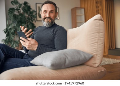 Caucasian Adult Man Is Sitting With Smartpone In Modern Cozy Office Lounge Zone