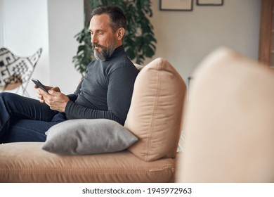 Caucasian Adult Man Is Sitting With Smartpone In Modern Cozy Office Lounge Zone