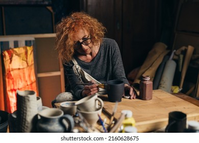 Caucasian Adult Woman Painting Pottery In Her Workshop