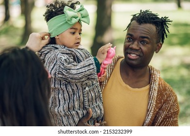 Caucasian and african american familiy relaxing while spending time together in the park on a weekend. Unconditional love between parents and children. Beautiful childhood.