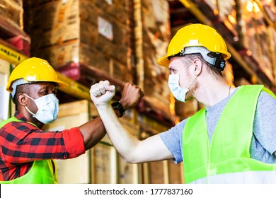 Caucasian and African American warehouse construction worker wearing protective face mask elbow bump greeting in New Normal adaptation to prevent Coronavirus spreading. Employee avoid touch in factory