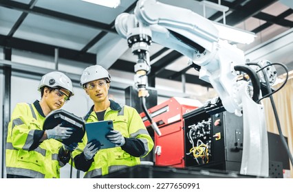 Caucasian american development technician engineer testing artificial intelligence robot arm at high technology research manufactue with equipment. Factory workers working with adept robotic arm. - Powered by Shutterstock