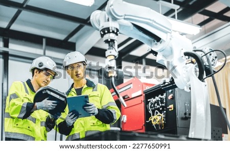 Caucasian american development technician engineer testing artificial intelligence robot arm at high technology research manufactue with equipment. Factory workers working with adept robotic arm.