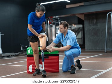 Caucasian assisted male physiotherapist take care Asia woman with prosthetic leg - Powered by Shutterstock