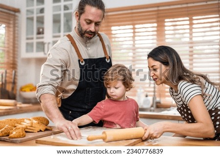 Caucasian attractive couple baking bakery with son in kitchen at home. Happy Family-father, mother and young boy having fun spending time together using ingredient making foods. Activity relationship.
