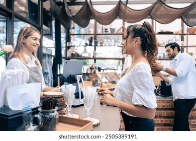 Caucasian attractive women receive coffee from waiter in coffee house. Young beautiful entrepreneur woman barista in apron give takeaway drink to customer in queue line on at urban restaurant cafe. - Powered by Shutterstock