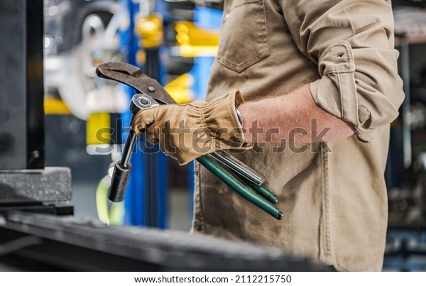 Caucasian Automotive Industry Worker with Car\
Repairing Tools in His Hands Close Up Photo. Transportation\
Industry Mechanic\
Job.