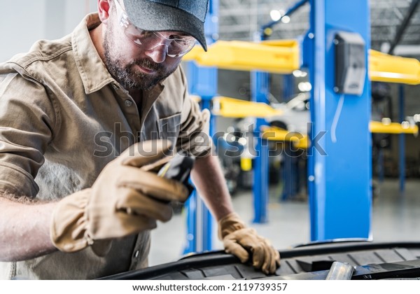 Caucasian Automotive Technician Worker Wearing\
Eyes Safety Glasses Repairing Broken Vehicle. Factory Recall\
Maintenance. Automotive Industry\
Theme.