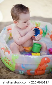 Caucasian baby boy playing with beach toys in childs swimming pool