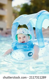 Caucasian baby boy in swimming circle toy swims at pool