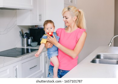 Caucasian Baby Infant Eating Fresh Red Apple. Happy Mother Feeding Baby Girl With Fruit. Organic Healthy Delicious Tasty Meal Snack For Children Kids. Lifestyle Authentic Family Moment.