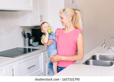 Caucasian Baby Infant Eating Fresh Green Apple. Happy Mother Feeding Baby Girl With Fruit. Organic Healthy Delicious Tasty Meal Snack For Children Kids. Lifestyle Authentic Family Moment.