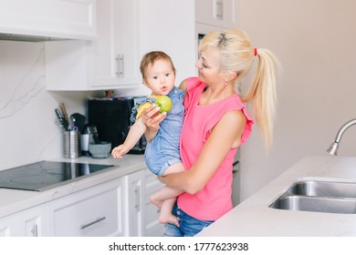 Caucasian Baby Infant Eating Fresh Green Apple. Happy Mother Feeding Baby Girl With Fruit. Organic Healthy Delicious Tasty Meal Snack For Children Kids. Lifestyle Authentic Family Moment.