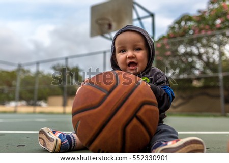 Caucasian Baby on Basketball Court in Athletic Clothes. 