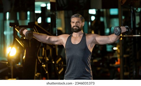 Caucasian beard muscular sport man is practice weight training on double dumbbells for biceps and triceps muscle inside the gym with dark background for exercising and workout - Powered by Shutterstock