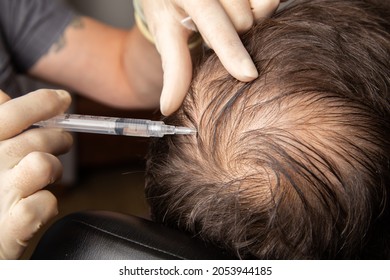 Caucasian bearded man receiving vitamin hairloss injections. Baldness prevention treatment at a plastic surgery clinic - Shutterstock ID 2053944185