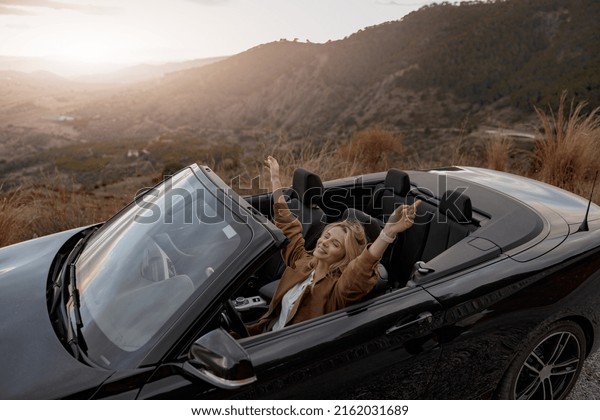 Caucasian beautiful happy relaxed\
woman in cabriolet traveling alone feeling free. Journey\
concept