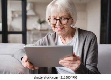 Caucasian beautiful old elderly senior woman lady grandmother using tablet for surfing social media, e-banking, e-commerce, checking pension, mortgage loan online at home - Powered by Shutterstock