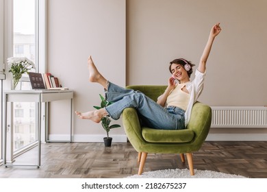Caucasian beautiful woman smiling at home in headphones . Short brunette hair young girl wearing blue jeans listen music at home. Use technology, lifestyle concept  - Shutterstock ID 2182675237
