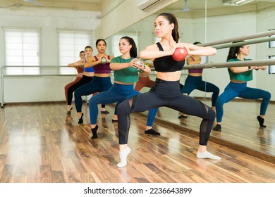 Caucasian beautiful woman teaching a barre class to an active group of women exercising - Powered by Shutterstock