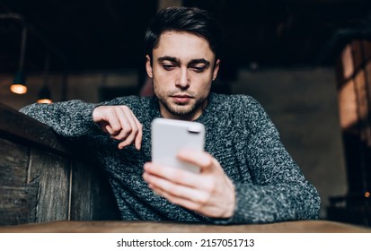 Caucasian blogger communicate via smartphone during leisure time using 4g wireless for browsing content text, millennial hipster guy checking email while messaging via cellphone technology