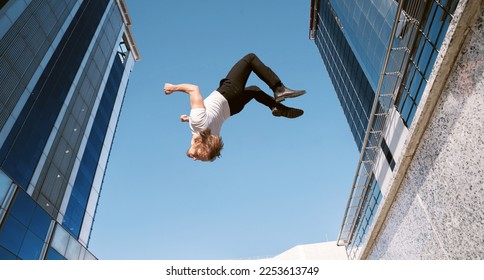 caucasian blond boy doing a backflip and parkour with blue sky in the background
					
					