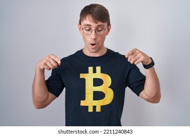 Caucasian Blond Man Wearing Bitcoin T Shirt Pointing Down With Fingers Showing Advertisement, Surprised Face And Open Mouth 