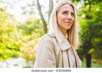 Caucasian blonde woman smiling happily on sunny summer or spring day outside walking in park. - Powered by Shutterstock