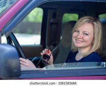 Caucasian Blonde Young Woman Driving In The Cab Of A Red Pickup Truck
