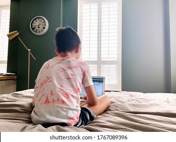 Caucasian Boy Child Sitting In Bed And Learning Online On Laptop Internet. Virtual Class Lesson On Video. Self Isolation At Home. Distant Remote Video Education. New Normal School Study For Kids.