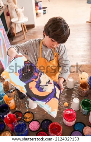 Caucasian boy of elementary age drawing picture at the fluid art technique at the art school